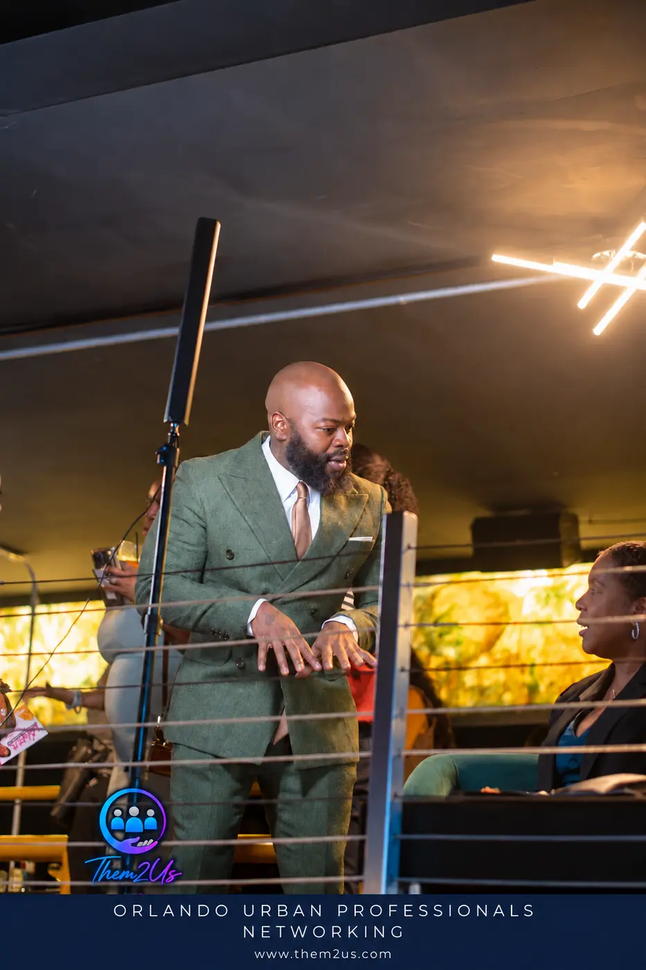Host on stage at Allure Lounge, Them2Us Urban Professionals Networking, Orlando, October 8, 2026